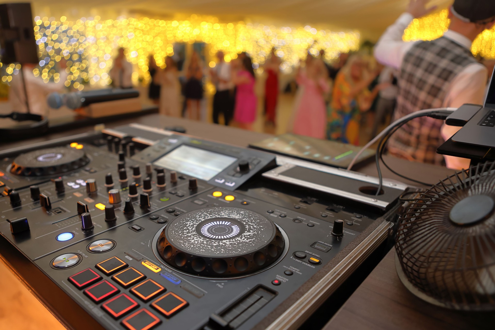 DJ table mixer closeup during the event or wedding party and dancing people