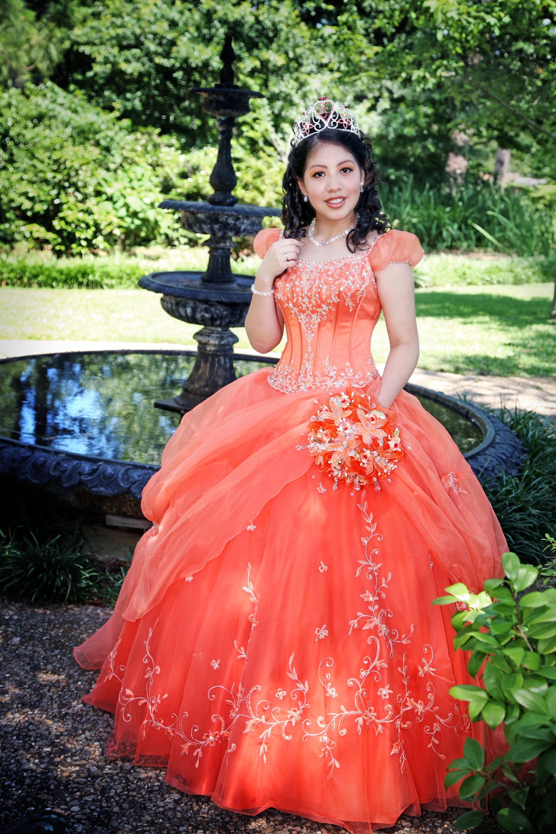 Quinceanera dressed up in beautiful ball gown, in a garden